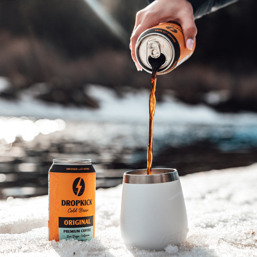 DropKick Brew Original Cold Brew can and coffee being poured into cup in the snow